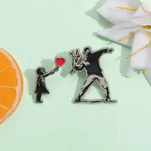 1. Pin´s artistiques Boutique Palestine représentant une scène de tendresse entre une enfant et un adulte, symbole d’amour et solidarité palestinienne.